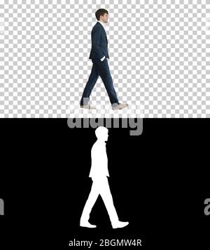 Handsome business man walking with his hands in pockets, Alpha C Stock Photo