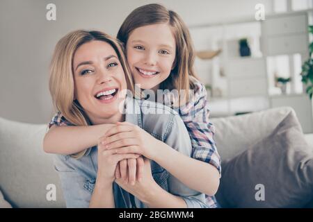 Closeup photo of domestic attractive blond lady mommy daughter sitting comfy couch hugging piggyback stay home quarantine spend weekend together best Stock Photo