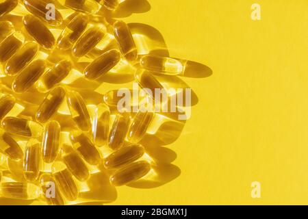 Close up of fish oil supplement product capsules isolated on yellow background. Stock Photo