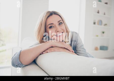 Closeup photo of domestic pretty charming blond lady relaxing sit comfy couch staying home good mood toothy smiling quarantine time spacious living Stock Photo
