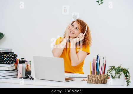 Young woman listening to music while working behind her desk Stock Photo