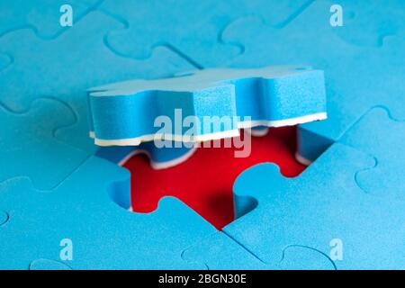 Jigsaw puzzle with one piece lifted up on red background Stock Photo