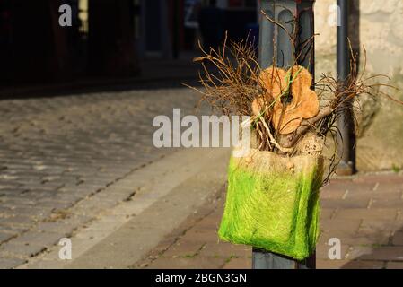 In the middle of the city, a decoration made of green fibers and artificial flowers was attached to a lamppost Stock Photo