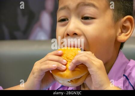 Hamburger fish in hand asia boy holding the eating. Stock Photo