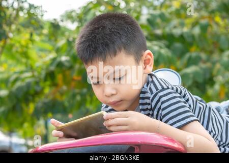 Portrait of Asian boys are playing mobile phones in park. Stock Photo