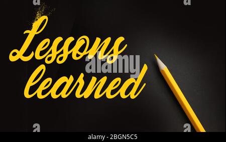 Leassons Learned words written on black with yellow pencil besides. Education or business crisis management concept Stock Photo