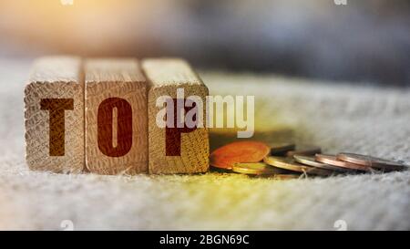 Top word written on wooden blocks and coins besides on burlap. Competitive market leader business concept