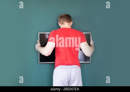 repair and decoration. 'husband for an hour' service. man hangs tv on the wall Stock Photo