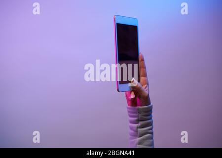 Close-up of man's hands with smartphone and blank black screen on blank purple background. Place for text Stock Photo