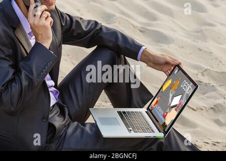 Man hand working with tablet illustration project while relaxing on couch. Back view of latin architect reading illustration on laptop. Stock Photo