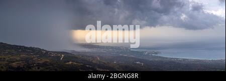 Panoramic view of a heavy downpour descends over Pafos (or Paphos) as seen from the Akamas Heights, Cyprus Stock Photo