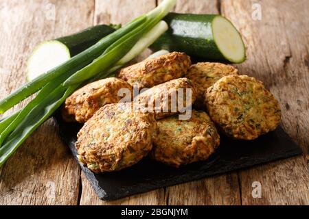 Mediterranean cuisine zucchini fritters with feta cheese close-up on a slate board on the table. Horizontal Stock Photo