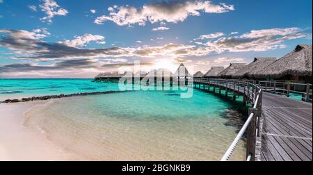 Scenic panoramic landscape view of luxury overwater bungalows at the beach and lagoon during sunset in Moorea, French Polynesia. Stock Photo