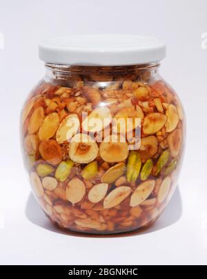 A jar of Greek honey and nuts (pistachios, peanuts, hazelnuts, pine nuts, almonds, walnuts) in natural light Stock Photo