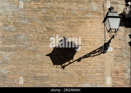 lantern casting shadow on stone wall Stock Photo