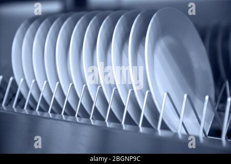 Rack steel storage of white clean dishes on shelf of professional kitchen Stock Photo