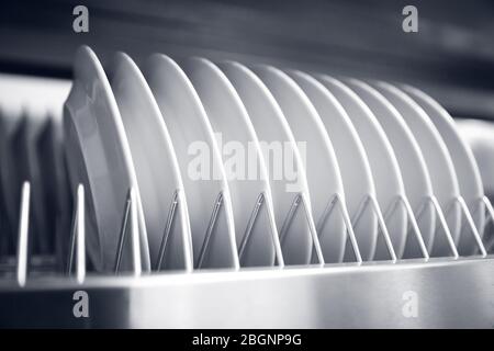 Rack steel storage of white clean dishes on shelf of professional kitchen Stock Photo