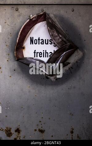 old dented metal sign Emergency exit free at weathered metal door with rust stains Stock Photo
