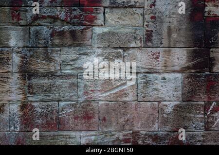 Close-up of an old weathered sandstone wall of different sized stones and texture with efflorescence and red, white and black spots of color Stock Photo