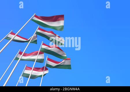 Hungary flags waving in the wind against a blue sky. 3D Rendering Stock Photo