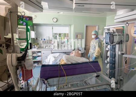 Gauting, Germany. 22nd Apr, 2020. Chief physician Lorenz Nowak (r) examines a corona patient who tested positive in protective clothing in an isolated intensive care bed room in the Asklepios Klinik. Doctors and hospitals are observing a worrying trend in the corona crisis. For fear of infection, far fewer patients with acute treatment needs come to the clinics. Credit: Peter Kneffel/dpa/Alamy Live News Stock Photo