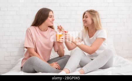 Two girlfriends talking, smiling and drinking fresh smoothie Stock Photo