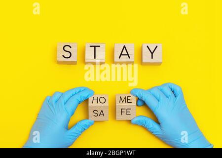 Written inscription stay home, stay safe on wooden blocks on yellow background. Stock Photo