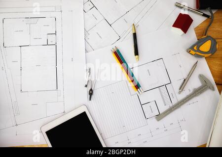 Construction blueprints with tools and tablet, top view. Tablet with architectural blueprints and measuring tools on wooden table. Stock Photo