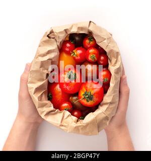 Woman holds eco paper bag full of fresh tomatoes Stock Photo