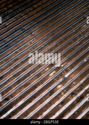 A sheet of corrugated metal, bent and scratched from heavy use over the years. Copper and brown in overall colouring. Stock Photo