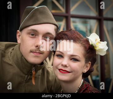 Front view, close-up portrait of 1940s young couple in love isolated outdoors, Black Country Museum, 1940s WWII wartime event UK. 1940s man & woman. Stock Photo