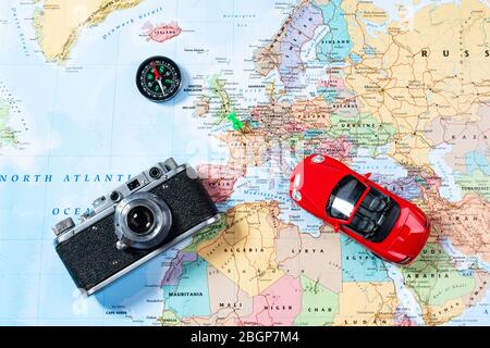 Model of red car, vintage camera and compass lie on Map of Europe. Concept of tourism, traveling on a car and taking photo in various countries of the Stock Photo