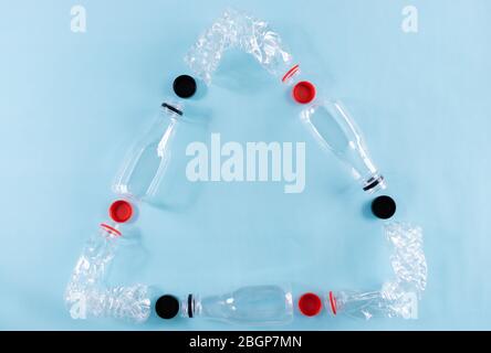 Six crashed plastic bottles on blue background form to recycling sign. Plastic utilization concept. Stock Photo