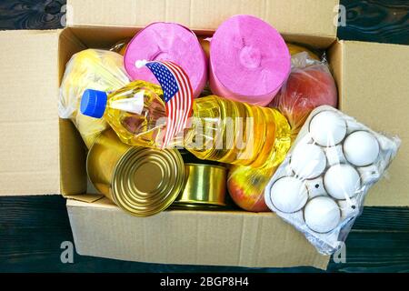 Packaged up different foodstuffs in donation box for poor. Canned food, oil, eggs, fruits, pasta. Top view, flat lay. Close-up. Indoors. Stock Photo