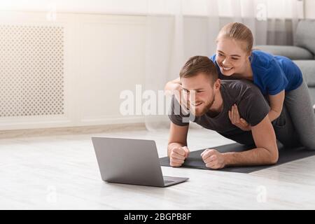 Cheerful couple training with personal fitness coach online Stock Photo