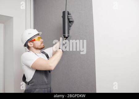 Electrician installs lamp lighting and spot loft style on ceiling Stock Photo