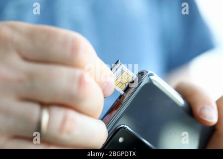 Male hands getting sim card slot of his smartphone out Stock Photo
