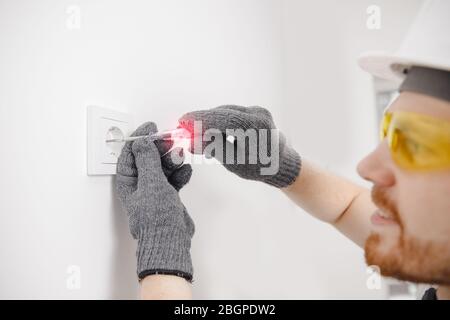 Electrician checks device for electricity voltage power outlet sockets Stock Photo