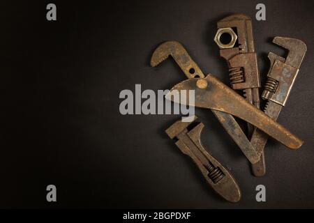 Old rusty wrench on black background, top view. Old dirty tools. Handmade. Household repairs. Stock Photo