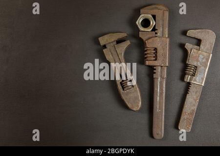 Old rusty wrench on black background, top view. Old dirty tools. Handmade. Household repairs. Stock Photo