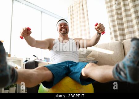 Funny smiling man sitting on fit ball working out Stock Photo