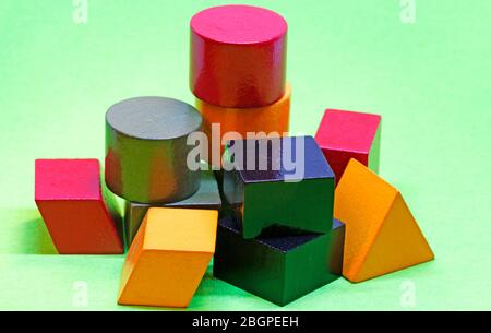wooden blocks in different colors and shapes on green background Stock Photo