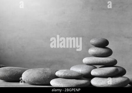 Stack of grey massage stones on grey background. Spa concept. Stock Photo