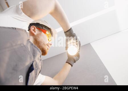 Electrician installs lamp lighting and spot loft style on ceiling Stock Photo