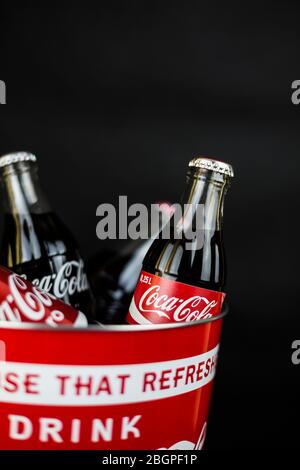 Atlanta, Georgia, USA – April 1, 2020: red bucket with bottles and cans of Coca Cola inscription drink coca cola, coke on black background vertical Stock Photo