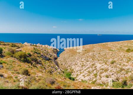 Blue Grotto in Malta. Pleasure boat with tourists runs. Natural arch window in rock Stock Photo