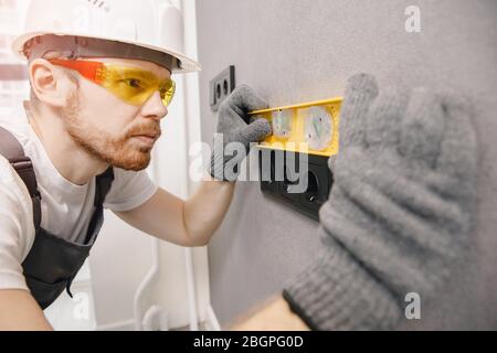 Electrician install switches and sockets checks tool levelness at home Stock Photo