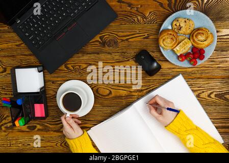 Laptop with cup of coffee on old brown wooden table. Top view to Notebook with cup of fresh coffee in home office in village. Stock Photo