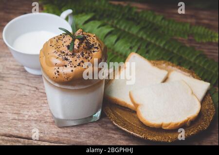 Dalgona coffee trendy Korean style on wooden plate with garden outdoor sun lighting. Stock Photo