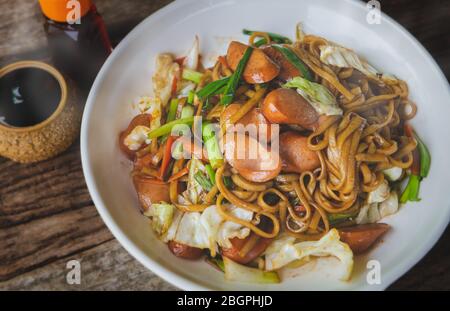 Yakisoba with sausage Japanese style fried noodle with sweet sauce in white plate with low sun lighting. Stock Photo